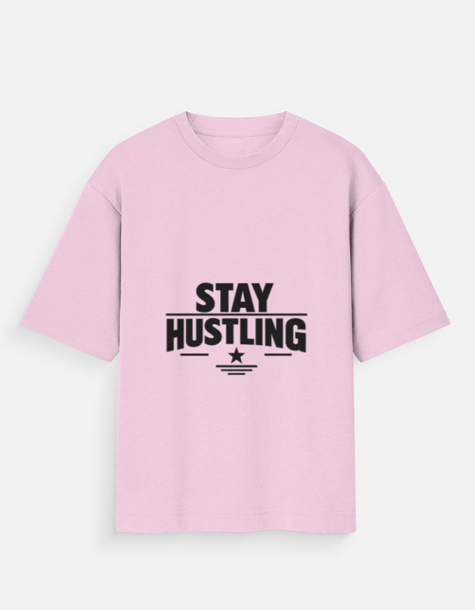 Oversized crew-neck T-shirt in light baby pink, short sleeves, front graphic text “STAY HUSTLING”